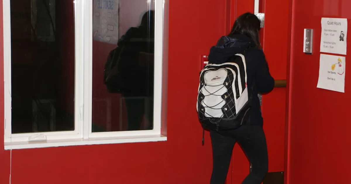 Studentin mit Rucksack betritt einen Wohnheim-Eingang.