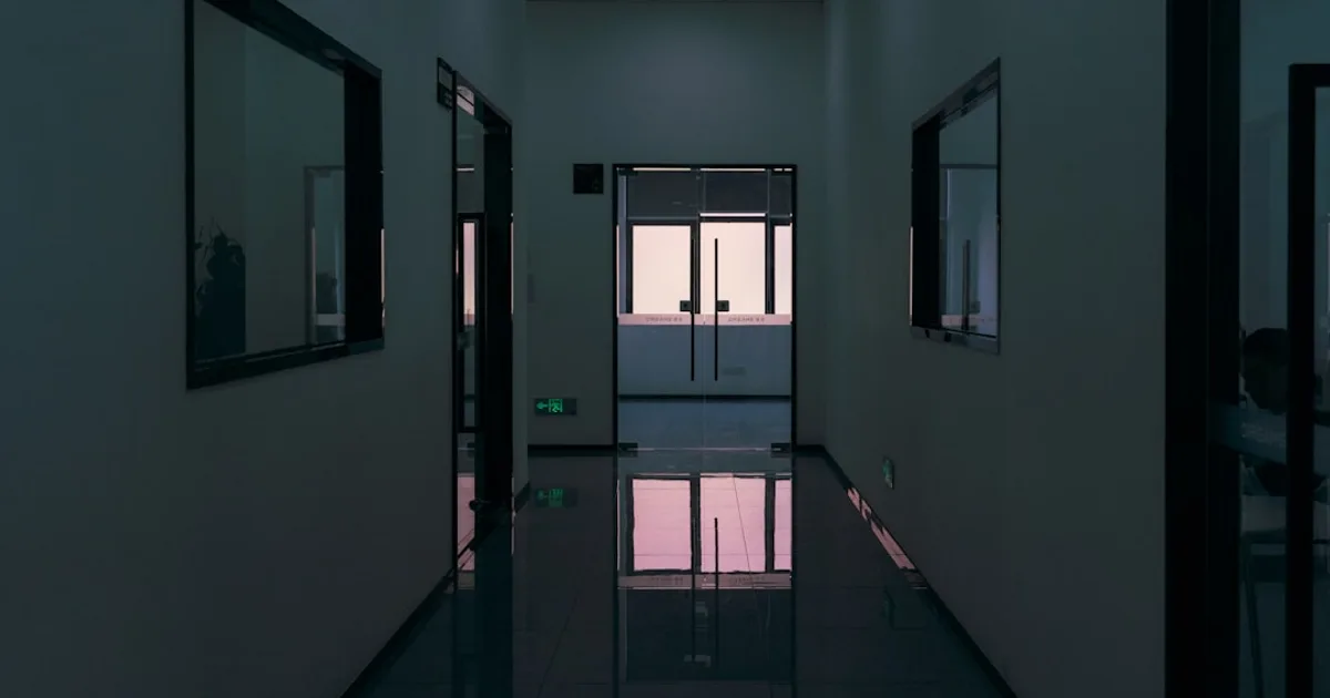 Moderner Büroflur mit reflektierendem Boden und Glasfronten.