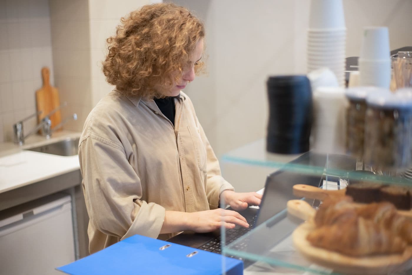 Café-Inhaberin pflegt am Tresen die Website ihres Cafés auf einem Laptop