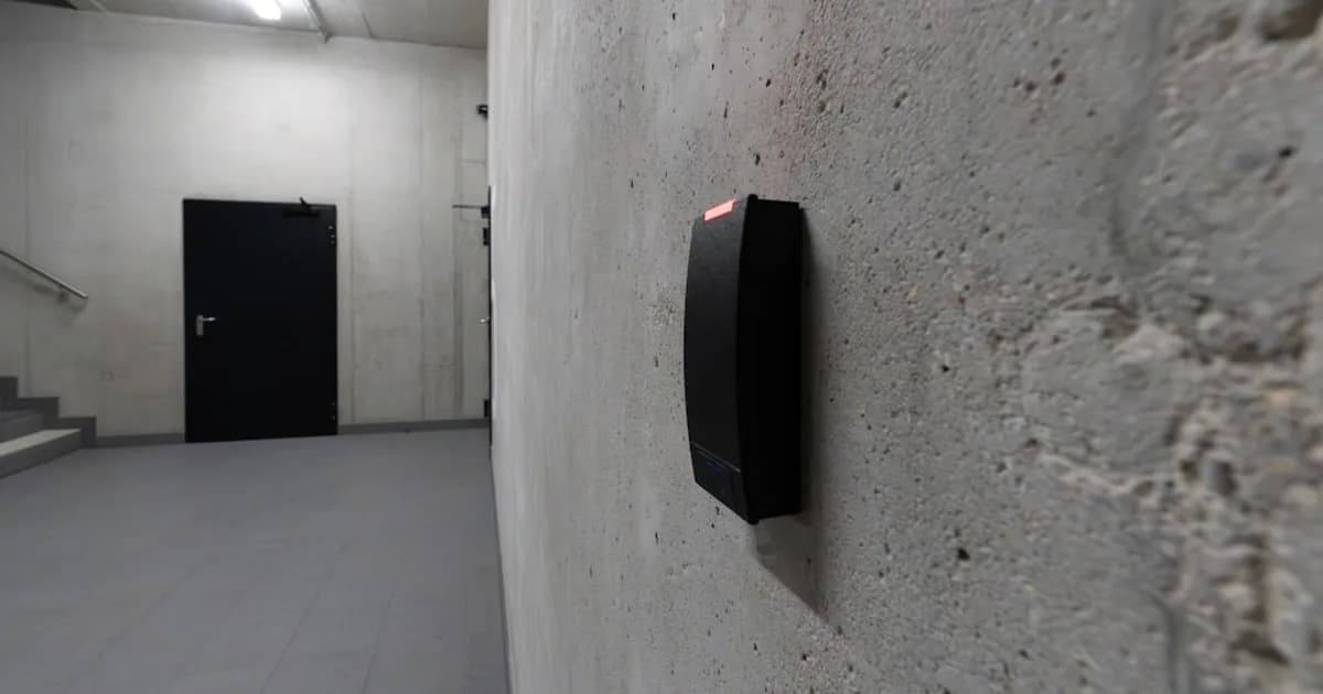 Eine Hand hält eine RFID-Karte vor einen Kartenleser an einer Bürotür.